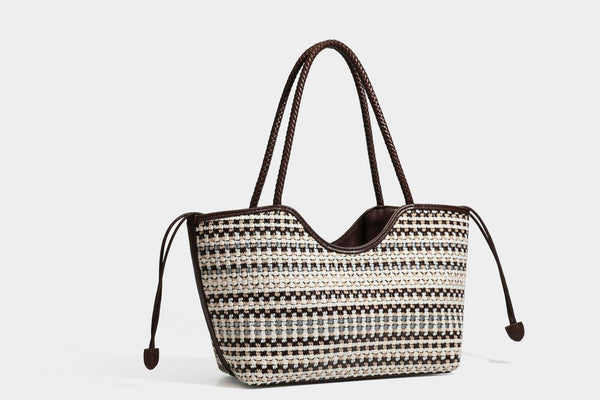 Large woven checker-pattern tote bag with dark braided shoulder straps, leather-look trim, and drawstring side ties, detail