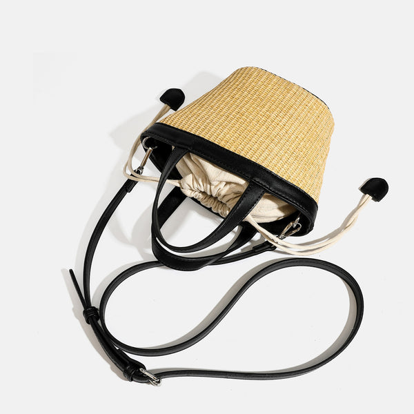 Kleine geflochtene Strohtasche in Beutelform mit schwarzem Besatz in Lederoptik, zwei Tragegriffen, cremefarbenem Zugbandfutter und seitlichen Kordelverschlüssen