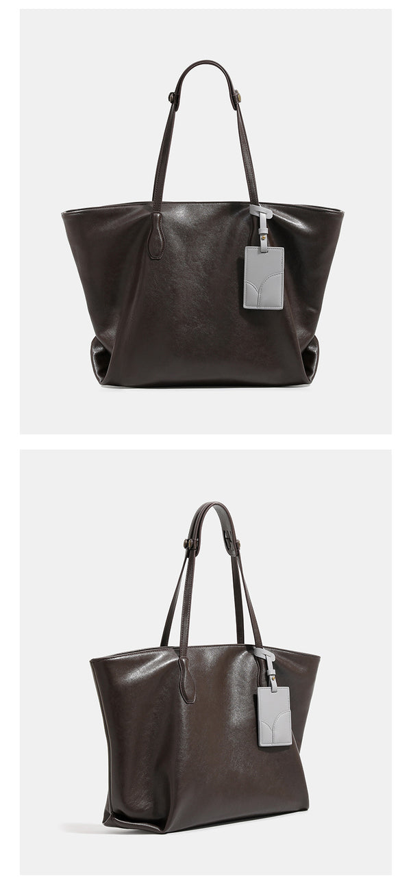 Large soft trapezoid tote bag with leather-look finish, dual shoulder straps, and gray hanging card tag, detail view 10