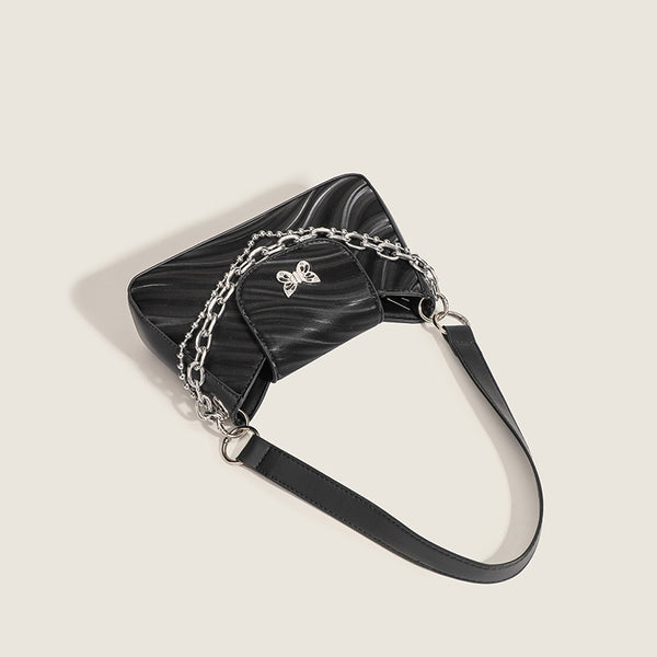 Small trapezoid shoulder bag with ripple leather-look finish, silver butterfly front clasp, and layered chain-and-ball strap