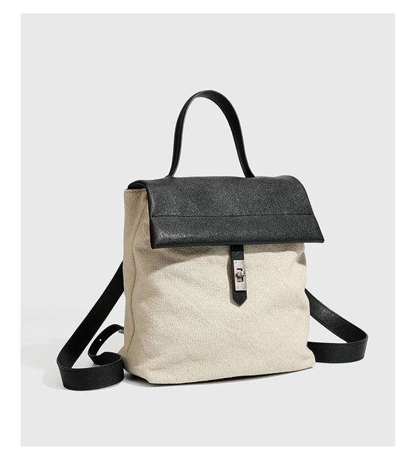 Strukturierter beigefarbener Rucksack aus gewebtem Canvas mit schwarzer Klappe in Lederoptik, Drehverschluss, Tragegriff und flachem Schulter