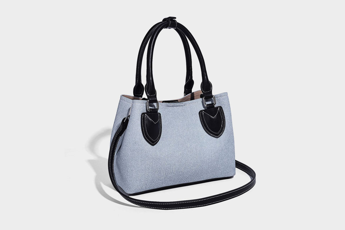 Structured light-blue denim-look tote bag with black leather-look handles, white contrast stitching, silver-tone hardware