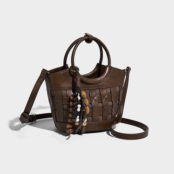 Small woven-panel bucket bag with circular ring handles, beaded tassel charm, and detachable crossbody strap in brown, front