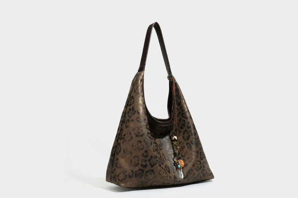 Lässige Hobo-Shopper-Tasche mit Leopardenmuster in Tan und Braun, dunkelbraunem Riemen in Lederoptik und herabhängendem Perlenanhänger an den Beschlägen