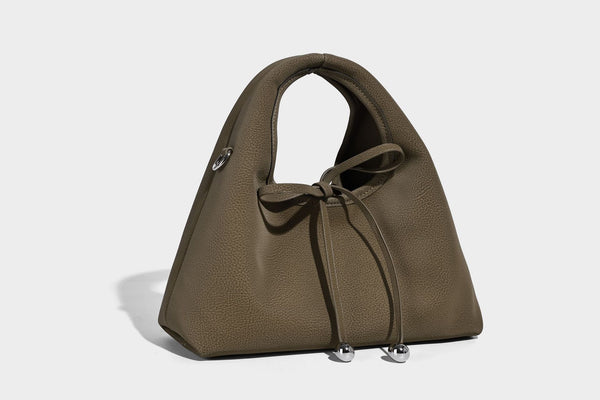 Pebbled matte trapezoid top-handle bag with drawstring bow closure, bead-tipped cords, silver-tone hardware, and detachable