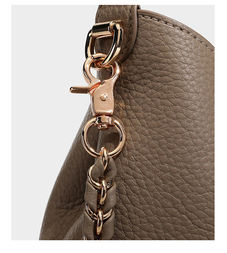 Schultertasche in genarbter Lederoptik im Hobo-Stil mit goldfarbener Kette, kurzem Tragegriff und dekorativem Anhänger an der Seite, Detailansicht
