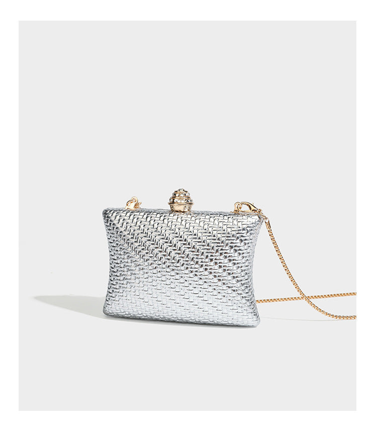 Small structured rectangular metallic woven-texture clutch bag with jeweled knob clasp and gold-tone chain strap, detail view