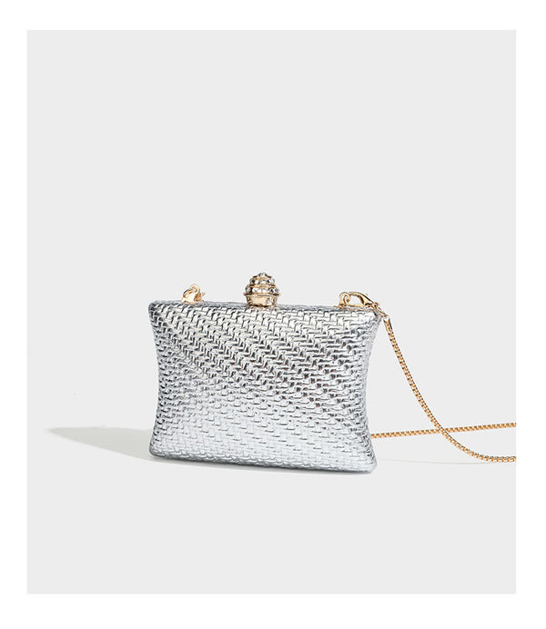 Small structured rectangular metallic woven-texture clutch bag with jeweled knob clasp and gold-tone chain strap, detail view