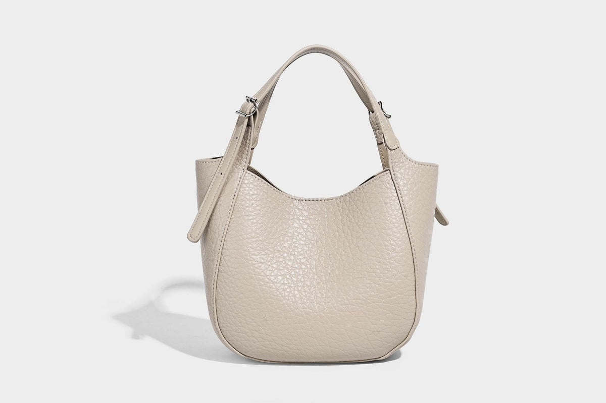 Small pebbled half-moon shoulder bag with dual top handles, detachable crossbody strap, and silver-tone hardware, detail view