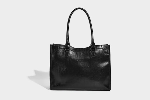 Large structured leather-look tote bag with front zip pocket, moto hardware accents, and long double shoulder straps, detail