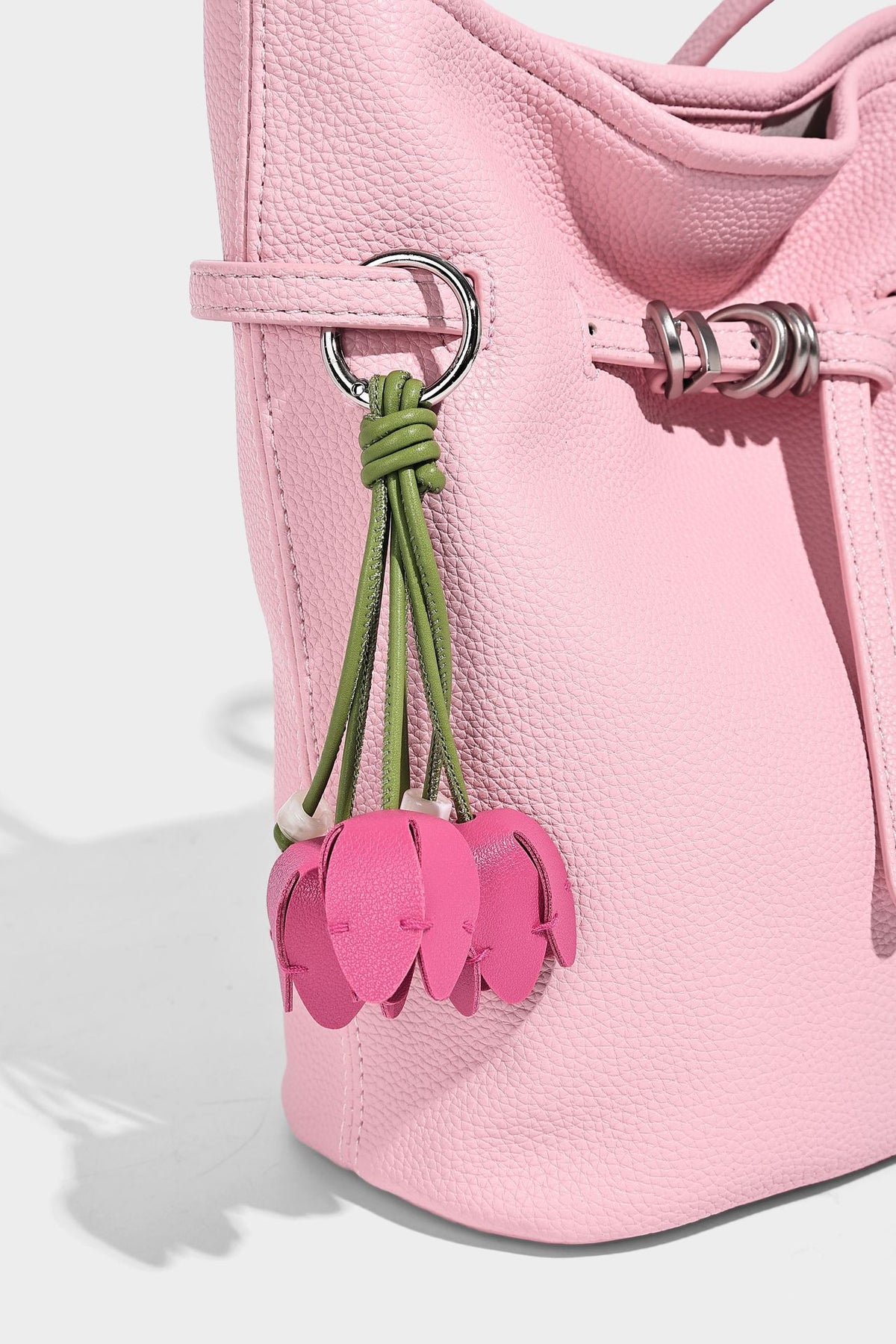 Small pebbled leather-look bucket bag with front drawstring toggle hardware and long adjustable shoulder strap, detail view