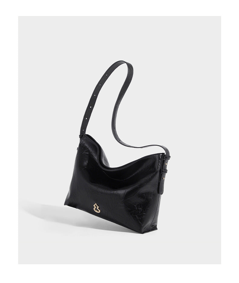 Large slouchy hobo shoulder bag in glossy crinkle leather-look finish with gold-tone emblem hardware and adjustable strap