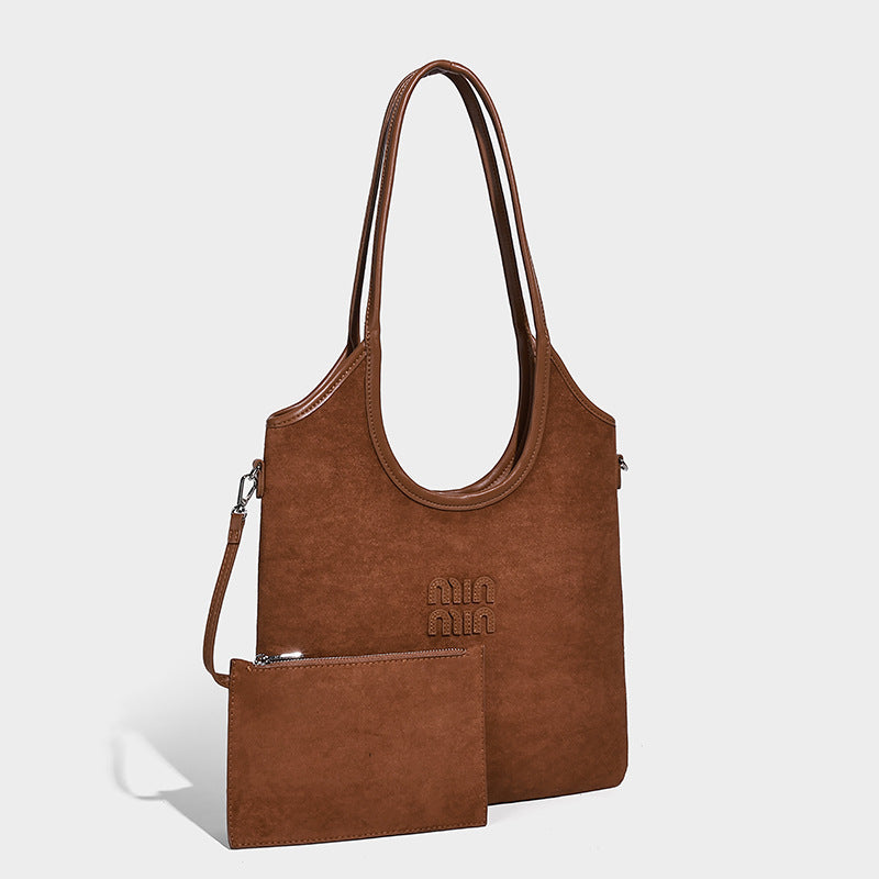 Warm brown matte suede-look tote bag with long top handles, embossed logo detail, silver-tone hardware, and matching, front