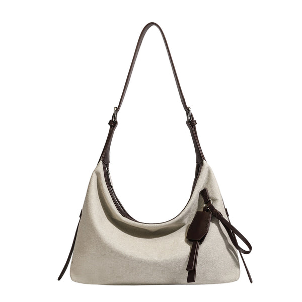 Cream canvas hobo shoulder bag with dark brown leather-look trim, zip-top closure, adjustable strap, and silver-tone