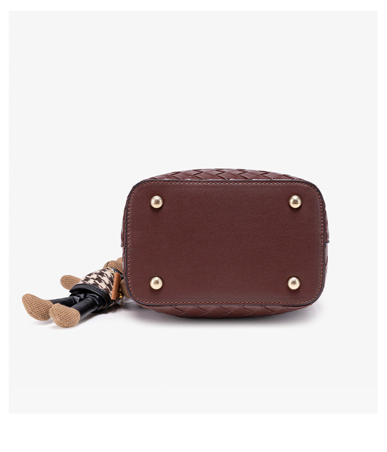 Brown woven-emboss leather-look bucket bag with short top handle, detachable crossbody strap, gold-tone hardware, and rabbit