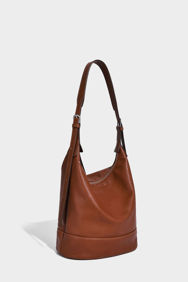 Slouchy bucket hobo shoulder bag in dark brown with glossy leather-look finish, top zip closure, and long adjustable, detail