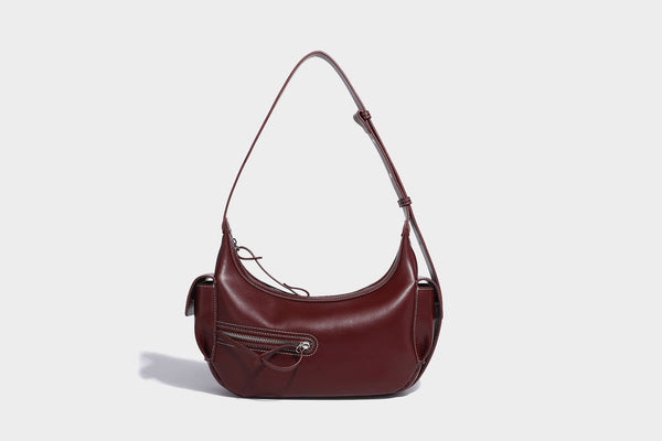 Smooth leather-look crescent shoulder bag with front zip pocket, side flap pockets, adjustable strap, and silver-tone, detail