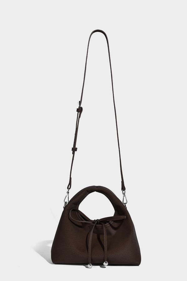 Pebbled matte trapezoid top-handle bag with drawstring bow closure, bead-tipped cords, silver-tone hardware, and detachable