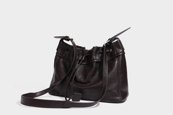 Lässig fallende Beuteltasche mit Kordelzug in dunkler Espresso-Lederoptik, verstellbarem Riemen und Ringbeschlägen aus Metall