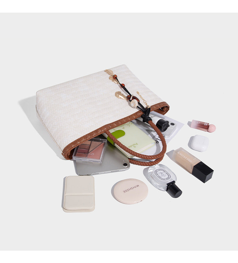Structured woven-texture tote bag with brown braided top handles, decorative tassel charm, and detachable shoulder strap