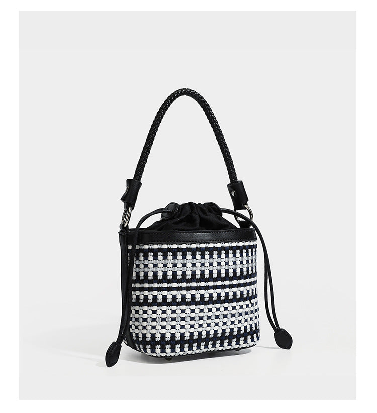Small structured woven checker bucket bag with braided top handle, drawstring closure, and silver-tone hardware in black