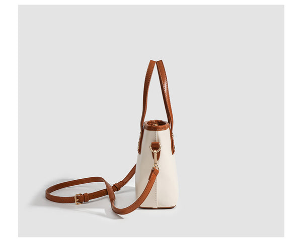 Kleine, formstabile Tote-Tasche mit Henkeln und Besatz in brauner Lederoptik auf einem cremefarbenen Korpus, Reißverschluss oben, goldfarbenen Nieten und