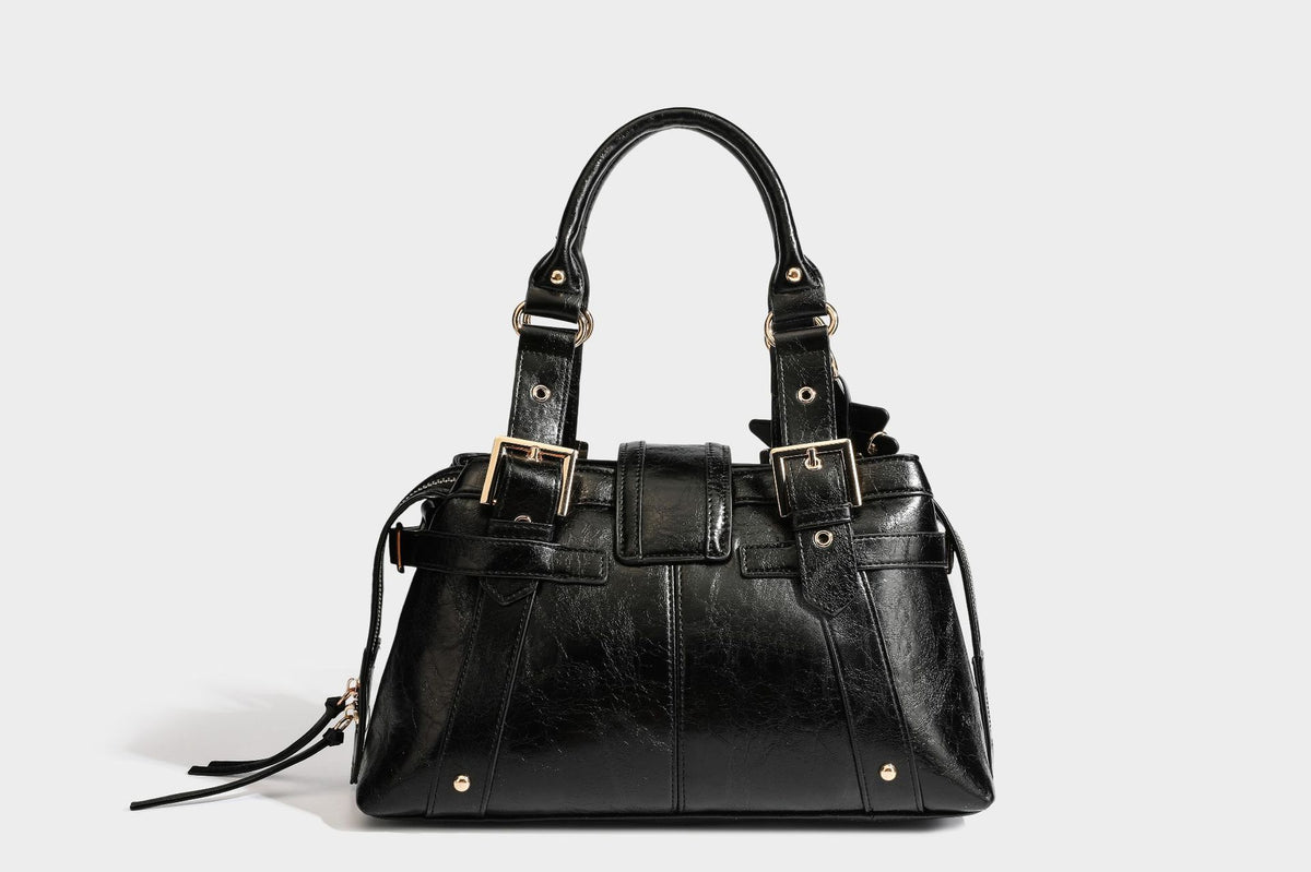 Structured leather-look satchel bag with heart padlock charm, star charm, gold-tone buckle hardware, dual top handles, and