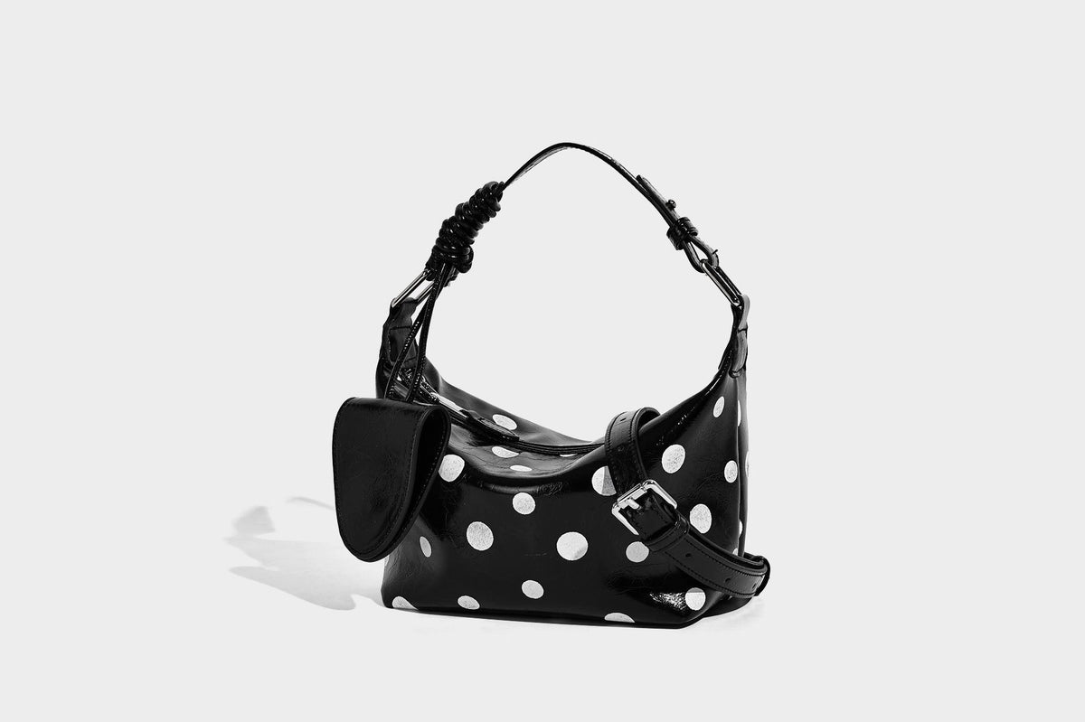 Kompakte glänzende Hobo-Schultertasche in Schwarz mit weißen Punkten, Reißverschluss, Beschlägen in Gunmetal und befestigtem Überschlag vorne