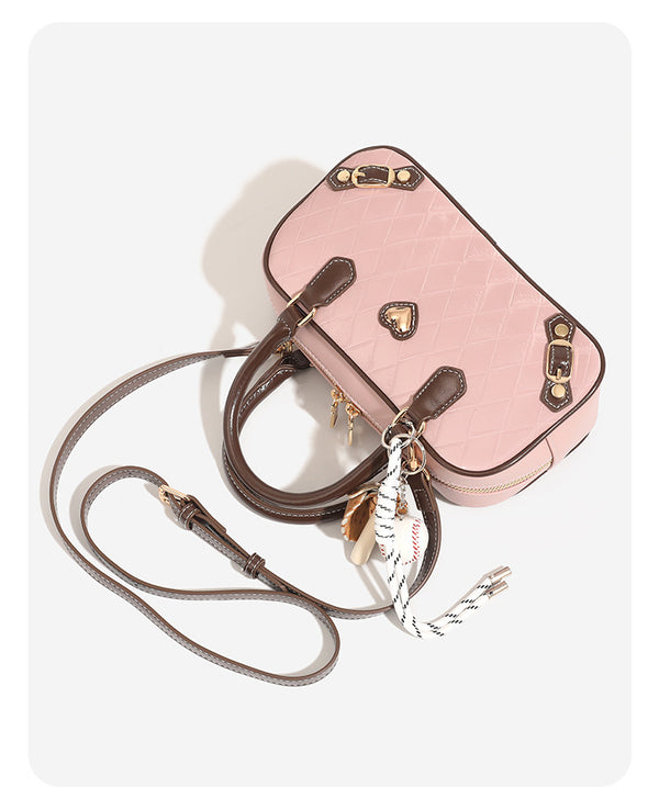 Blush pink quilted bowling barrel bag with dark brown leather-look trim and handles, baseball bat and ball charm, gold-tone