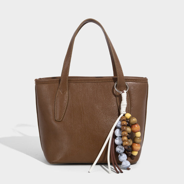 Compact structured bucket tote bag with pebbled textured finish, dual top handles, silver-tone lock hardware, and detachable