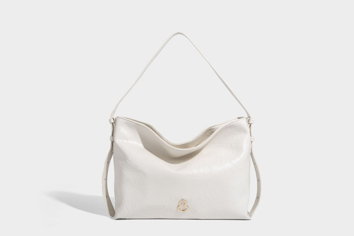 Large slouchy hobo shoulder bag in glossy crinkle leather-look finish with gold-tone emblem hardware and adjustable strap