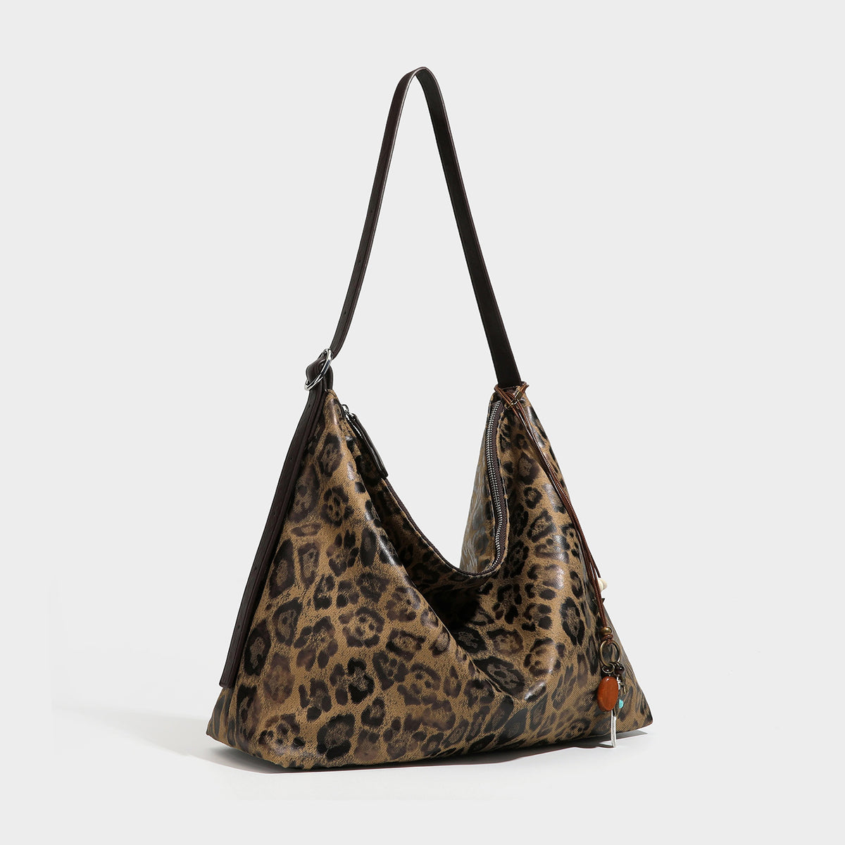 Slouchy leopard print hobo shoulder bag with glossy coated finish, top zipper closure, dark brown trim, and dangling charm