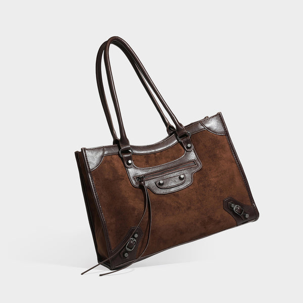 Large structured tote bag with matte suede-like body, smooth leather-look trim, front zip pocket, stud hardware, and