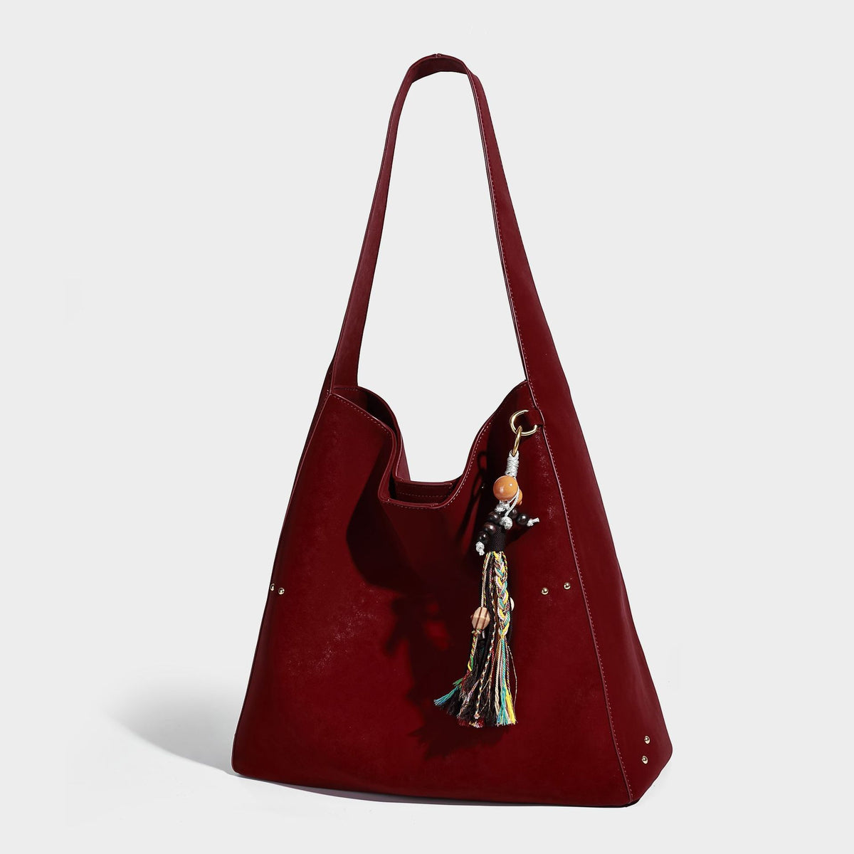 Oversized trapezoid tote bag with matte leather-look finish, gold-tone rivets, and long shoulder strap, detail view 7