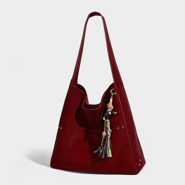 Oversized trapezoid tote bag with matte leather-look finish, gold-tone rivets, and long shoulder strap, detail view 7