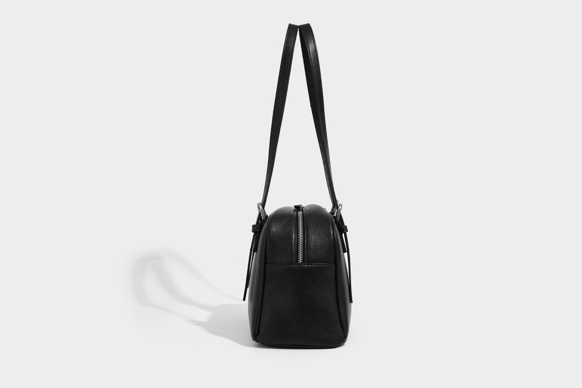 Structured dome-shaped shoulder bag with leather-look finish, top zipper closure, dual adjustable slim straps, and, detail