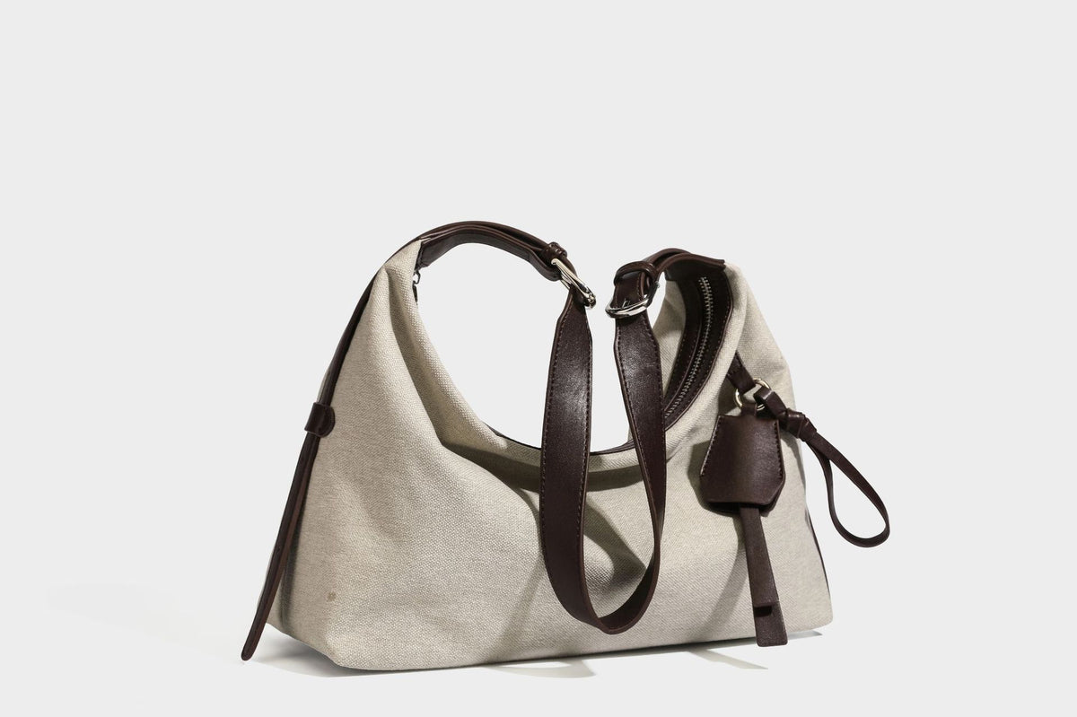 Lässige Hobo-Schultertasche aus haferfarbenem Canvas mit dunkelbraunen Besätzen in Lederoptik, silberfarbenem Reißverschluss und langem, verstellbarem