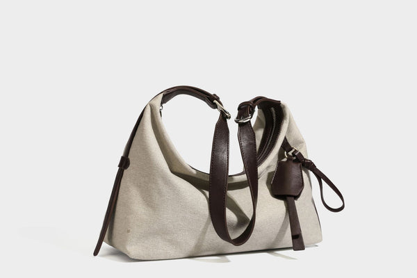 Lässige Hobo-Schultertasche aus haferfarbenem Canvas mit dunkelbraunen Besätzen in Lederoptik, silberfarbenem Reißverschluss und langem, verstellbarem