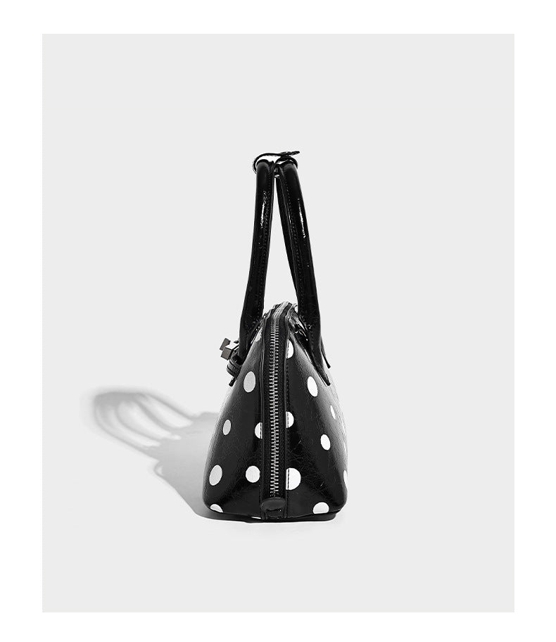 Structured polka-dot Boston bag with glossy crinkled finish, dual top handles, silver-tone turn-lock clasp, and detachable