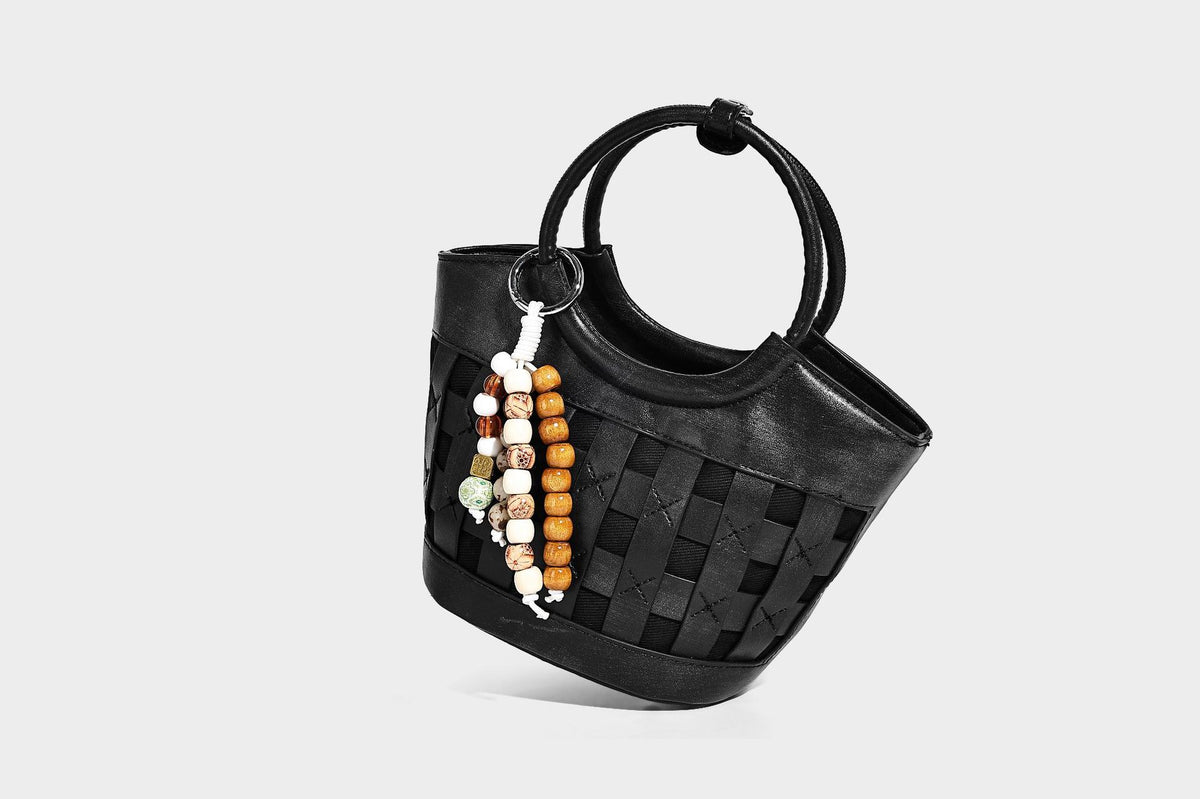 Kleine, formstabile Flecht-Bucket-Bag mit rundem Henkel, Perlenanhänger und abnehmbarem Schulterriemen in Lederoptik