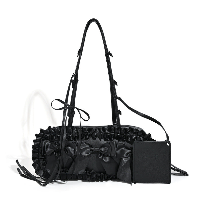Black leather-look structured tote bag with gathered ruffle trim, ribbon bow accents, top zip closure, and attached card