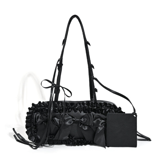 Black leather-look structured tote bag with gathered ruffle trim, ribbon bow accents, top zip closure, and attached card