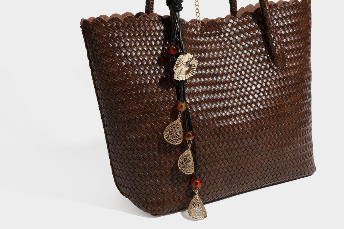 Large open-top woven leather-look tote bag in dark brown with scalloped edge, braided double shoulder straps, and decorative