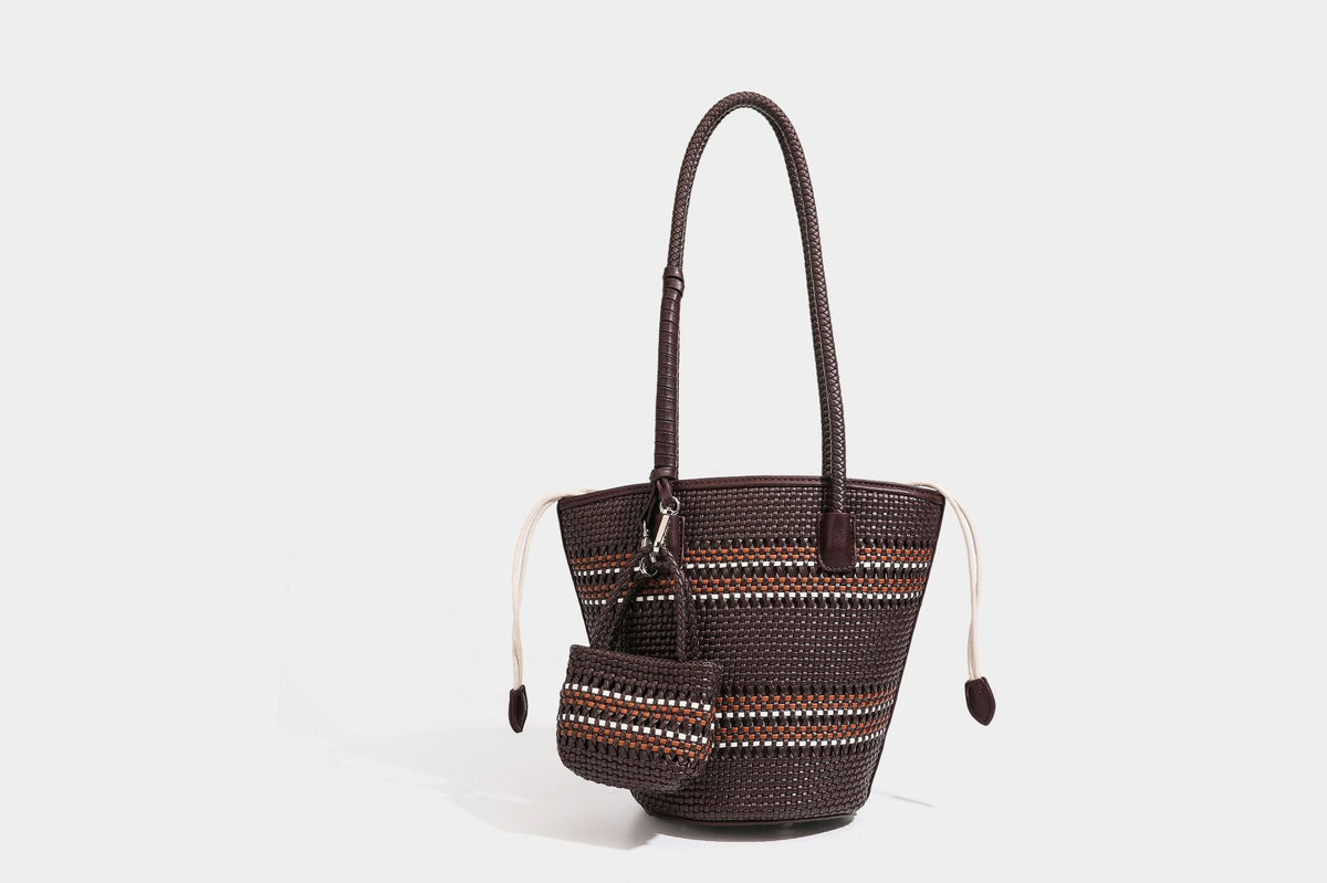 Light blue open-weave woven bucket tote bag with long braided shoulder straps, drawstring side ties, and attached mini pouch