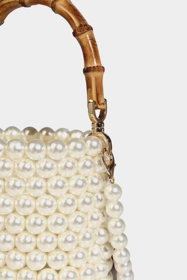 Small cylindrical bucket bag with glossy faux-pearl bead exterior, bamboo arched top handle, satin drawstring closure, and