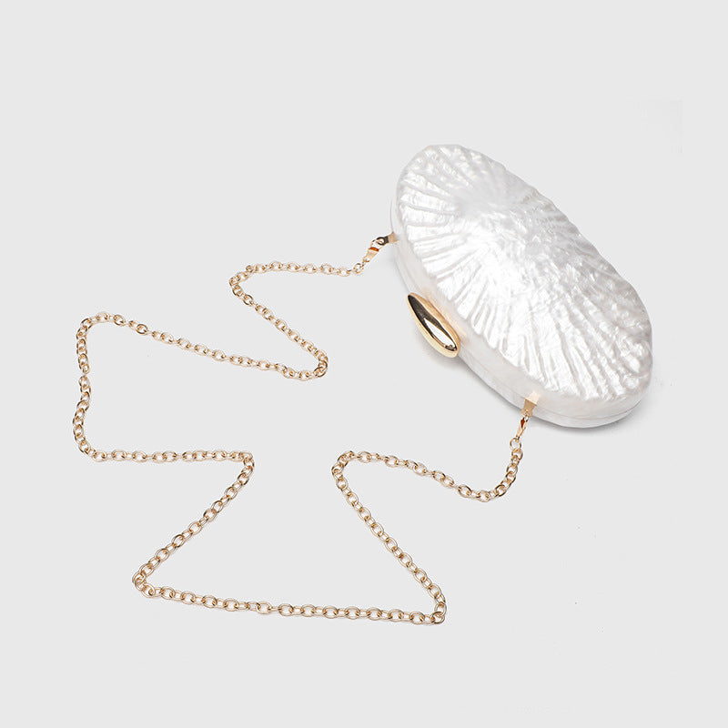 Oval pearl-finish shell clutch bag with gold-tone clasp and removable gold link chain strap, detail view 3