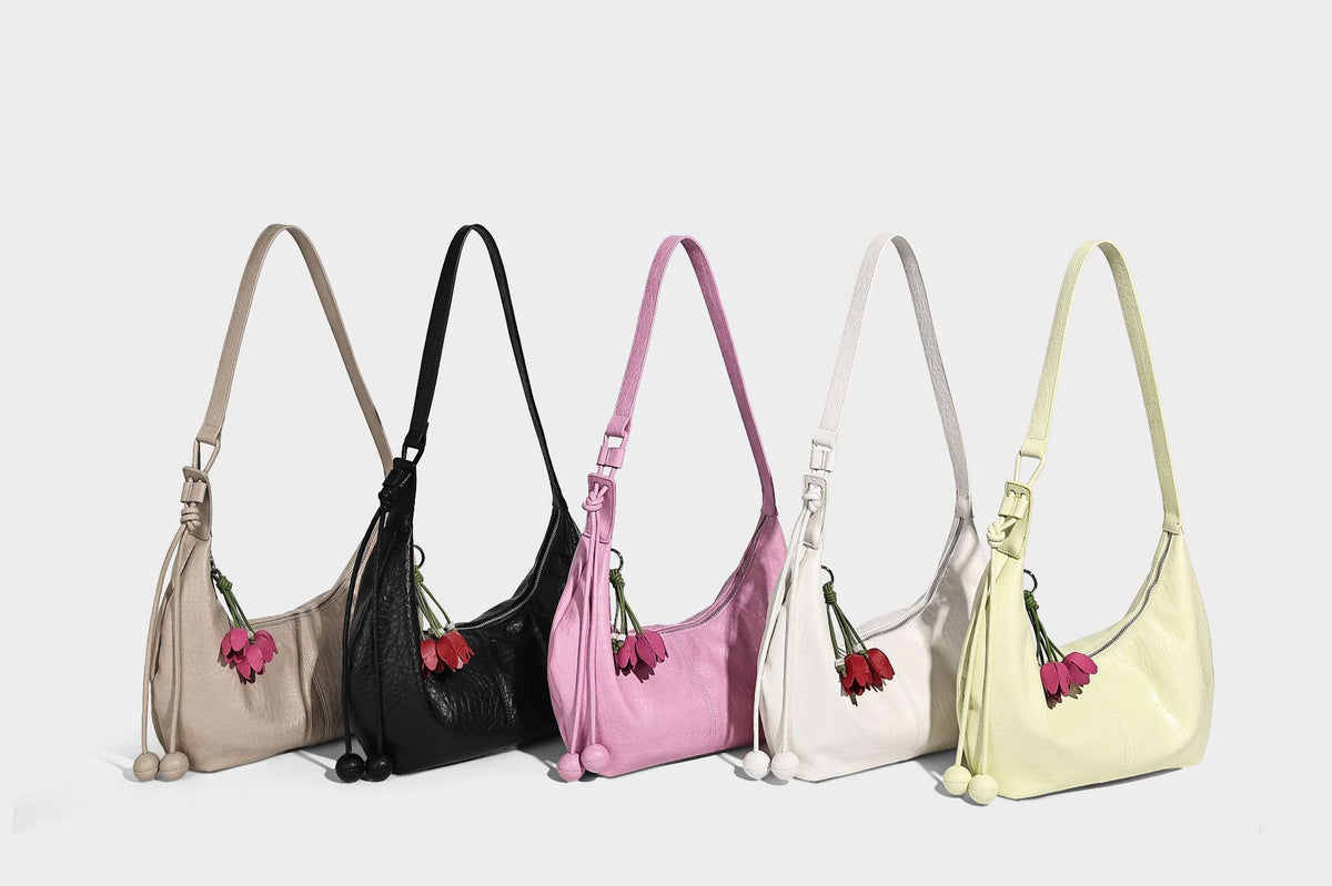 Slouchy crescent half-moon shoulder bag in pink pebbled textured finish with floral charm and knotted side detail, detail