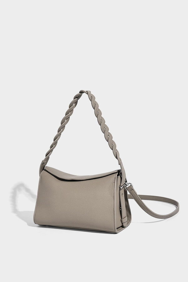 Small structured pebbled-finish shoulder bag with braided top handle, detachable crossbody strap, floral tassel charm, and