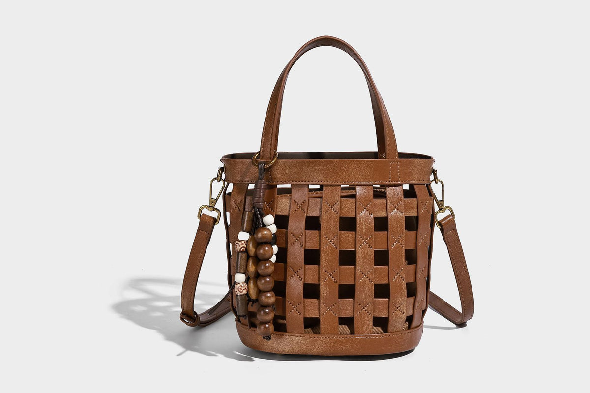 Small woven lattice bucket bag in brown leather-look finish with beaded tassel charm, dual top handles, and detachable