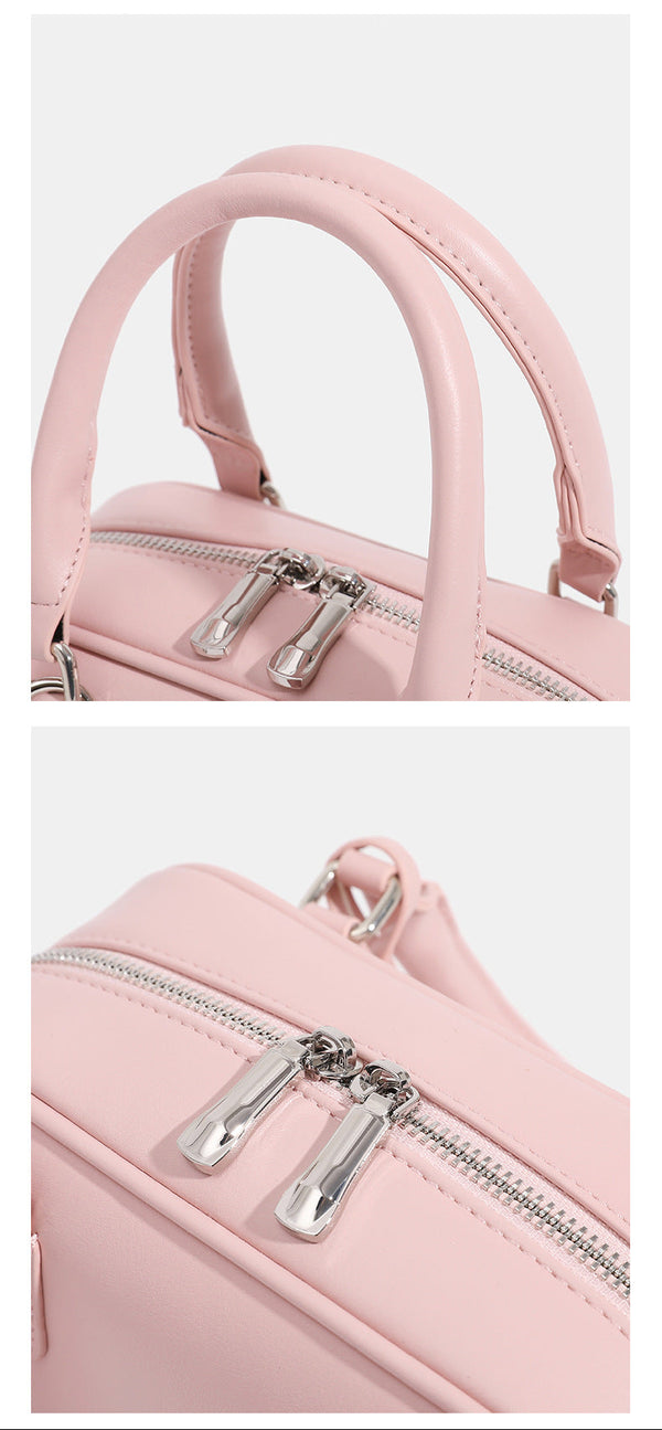 Small structured rounded-rectangle mini handbag with glossy leather-look finish, top zip closure, silver-tone hardware, and